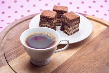 Uma xícara com café e palha italiana sobre madeira, sobre superfície cor-de-rosa. 