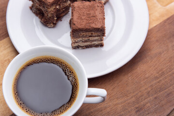 Uma xícara de café com pedaços de palha italiana sobre superfície de madeira.