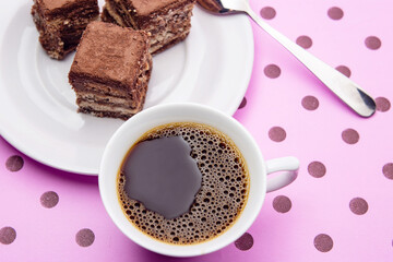 Uma xícara de café e pedaços de palha italiana sobre superfície cor-de-rosa.