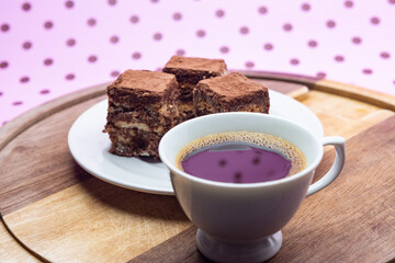 Uma xícara com café e palha italiana sobre madeira, sobre superfície cor-de-rosa. 