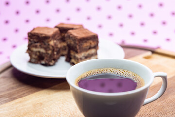 Uma xícara com café e palha italiana sobre madeira, sobre superfície cor-de-rosa. 