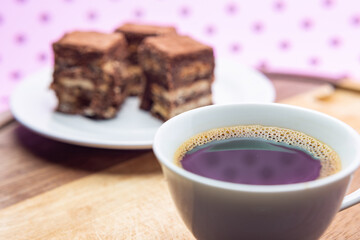Uma xícara com café e palha italiana sobre madeira, sobre superfície cor-de-rosa. 