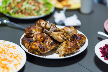 Chicken shanks, chicken legs are served on a plate with various salad plates in the background. High quality photo
