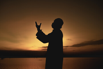 Fototapeta premium Silhouette Young asian muslim man praying on sunset,Ramadan festival concept