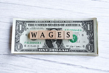 Wages word written on wood block with American Dollar-bills. Directly above.