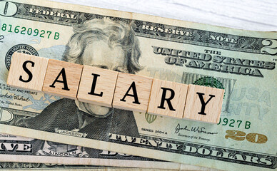 Salary word written on wood block with American Dollar-bills. Directly above.