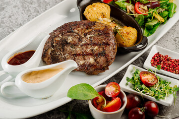 Roasted meat steak with fried potatoes, mushrooms, tomatoe sauce and herbs