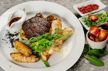Roasted meat steak with fried potatoes, mushrooms, tomatoe sauce and herbs