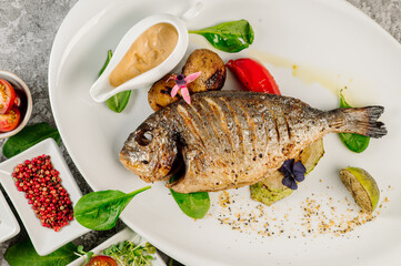 Grilled whole dorada fish with sauce and vegetables. Top view