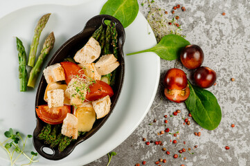 Dish of boiled vegetables in bowl with herbs on grey concrete background