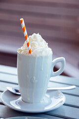 Heißgetränk mit Sahnehaube und Papierstrohhalm