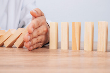 hand stops falling dominoes or wooden puzzle