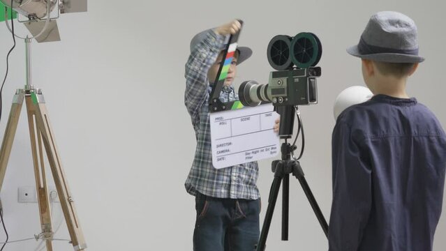 Children with hats play in a studio with loudspeaker, filming claps m reflector, future director stage and actor