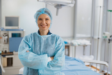 Smiling female surgeon standing in operating room with crossing hands, ready to work on patient