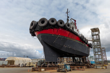 Red and black tug boat in dry dock
