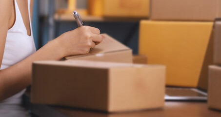 selling products online. A young woman is packing products to send to customers online.