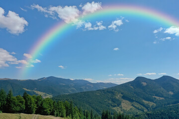 Picturesque mountain landscape and beautiful rainbow in blue sky