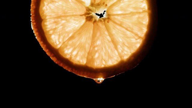 Juicy orange slice on black background. Citrus fruit close-up texture, healthy sweet food. Summer refreshment concept.