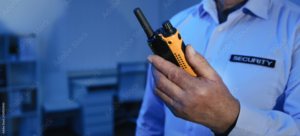 Wall mural professional security guard with portable radio set in dark room, closeup. banner design