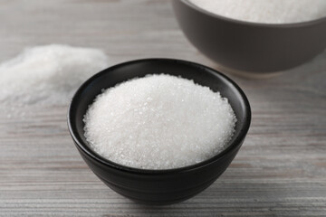 Granulated sugar on light wooden table, closeup