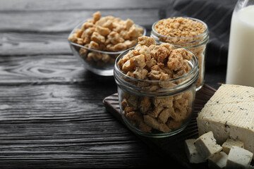 Different natural soy products on black wooden table, closeup. Space for text