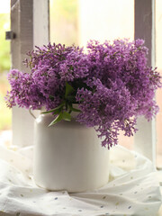 Fototapeta na wymiar Beautiful lilac flowers in vase on window sill indoors