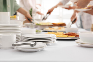 Fototapeta na wymiar People taking food during breakfast, focus on clean dishware. Buffet service