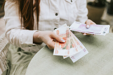 money rubles, dollars, euros in hands young beautiful woman model plus size sit home garden,...