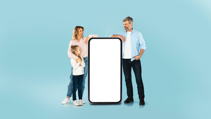 Family Leaning On Mobile Phone With Empty Screen, Blue Background