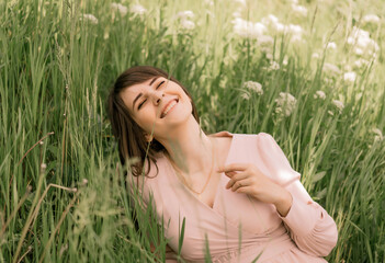 a girl in a pink dress sits in the grass and enjoys the sun
