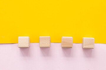 Wooden cubes on yellow-pink background