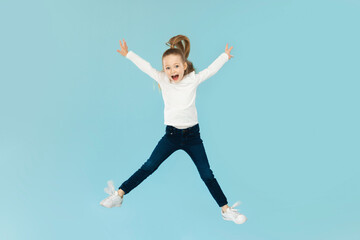 Obraz premium Joyful Little Girl Jumping Having Fun Posing, Blue Background