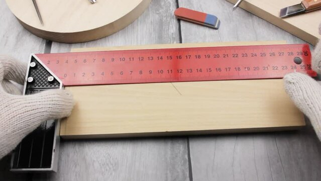 A man draws with a ruler on a wood carving board. Carpentry work. Wood master.