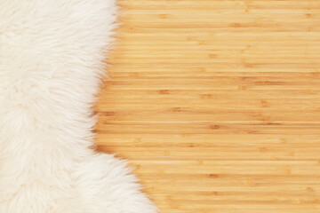 White fur rug on a wooden background. Natural wooden background with white sheep skin. Scandinavian aesthetics. Nordic, hygge, lagom, cozy home concept. Flat lay