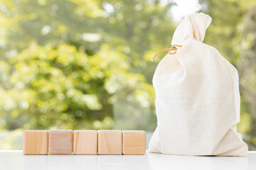 Full brown canvas bag with and wooden blank cubes on green summer background. Wealth