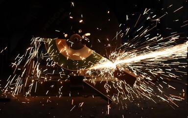 Scene of sparks flying from the iron while cutting metal with a grinder.
