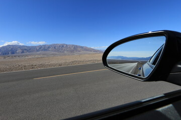 road in the desert valley of death view from the mirror of a car