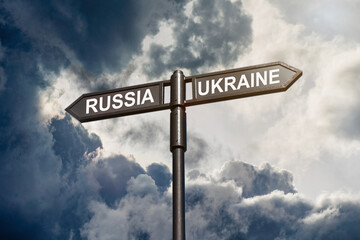 Fototapeta premium Road sign with inscriptions Russia and Ukraine against a stormy sky. Russian aggression against Ukraine
