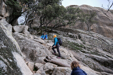Fototapeta premium A family clambering over some rocks, hiking in the mountains.