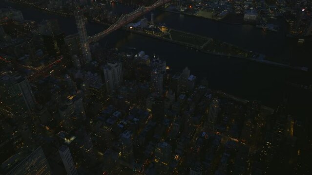 Forwards fly above evening city. High angle view of illuminated Queensboro Bridge. Manhattan, New York City, USA