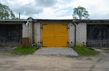 Fototapeta na wymiar yellow wooden garage door between two unpainted