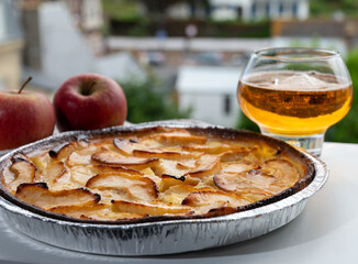Apple products of Normandy, homemade baked apple cake and cider drink and houses of Etretat village on background, Normandy, France