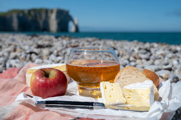 Lunch on pebbles beach of Etretat, french cheese camembert and apple cider drink with chalk cliffs...