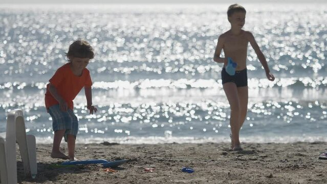 Happy children brig water bring sea water to build on seashore, summer panorama