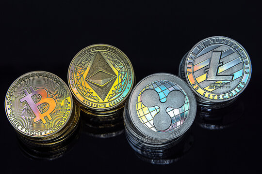 Horizontal view of cryptocurrency tokens, including Bitcoin, Ethererum Ripple, and Litecoin saw from above on black background. High quality photo