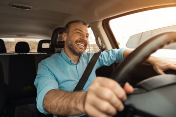 Happy man in earphones enjoying music driving luxury car - obrazy, fototapety, plakaty