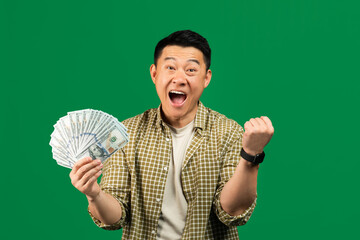 Overjoyed mature asian man with lots of money making YES gesture, shouting at camera over green...