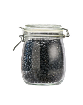 Heap of uncooked black beans grains in glass storage jar isolated on white background.
