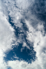 Blue sky with cumulus white clouds. Beautiful cloudscape. Abstract background. Vertical orientation.