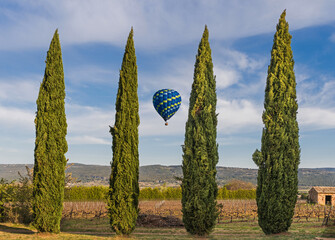 Hot air balloon flight between cypresses in the vaucluse near the village of Roussillon, France